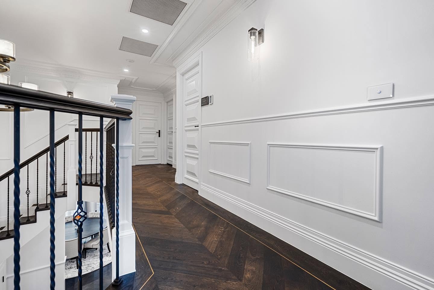 Dark-stained chevron oak hallway with a curved staircase