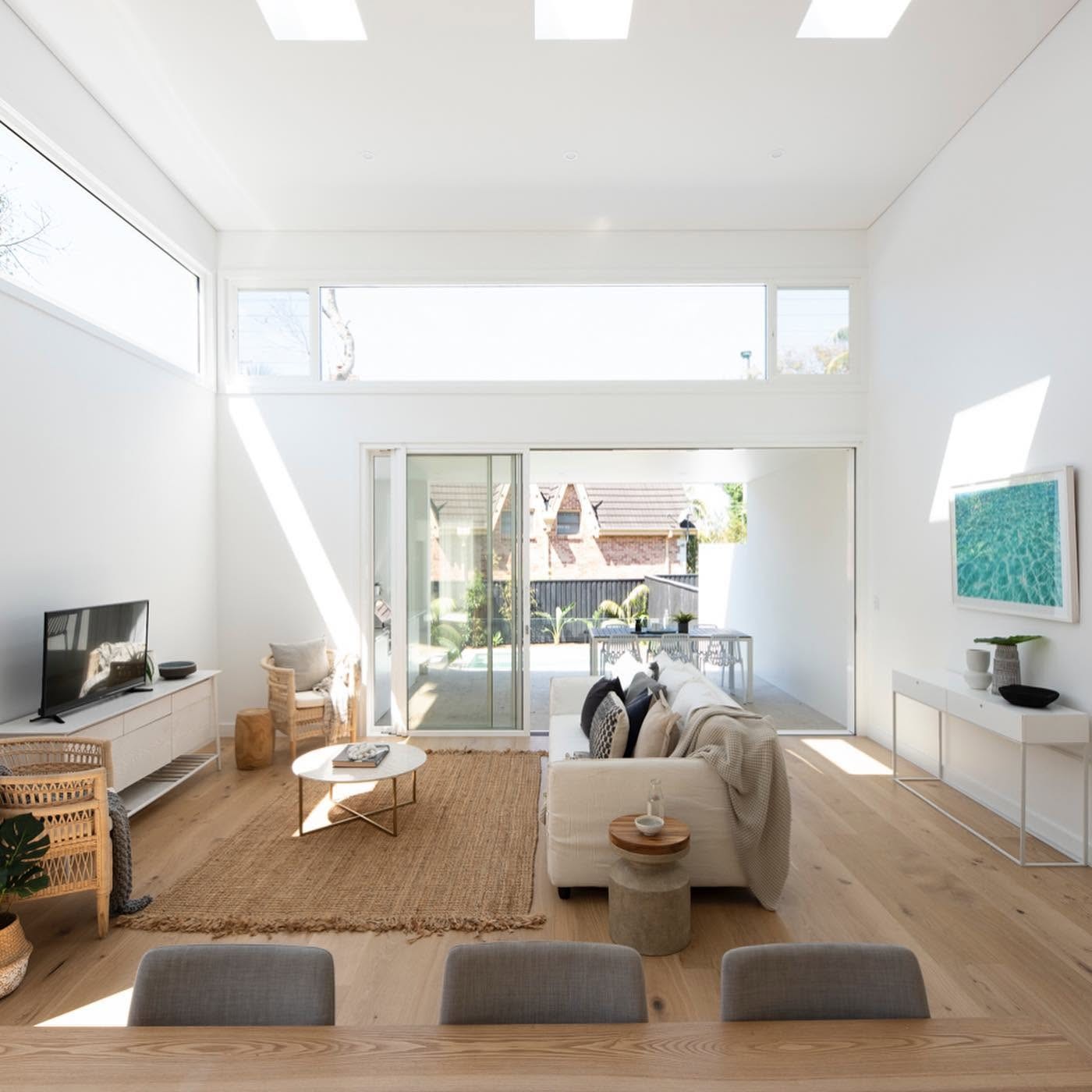 Bright living room with light oak flooring opening to a courtyard