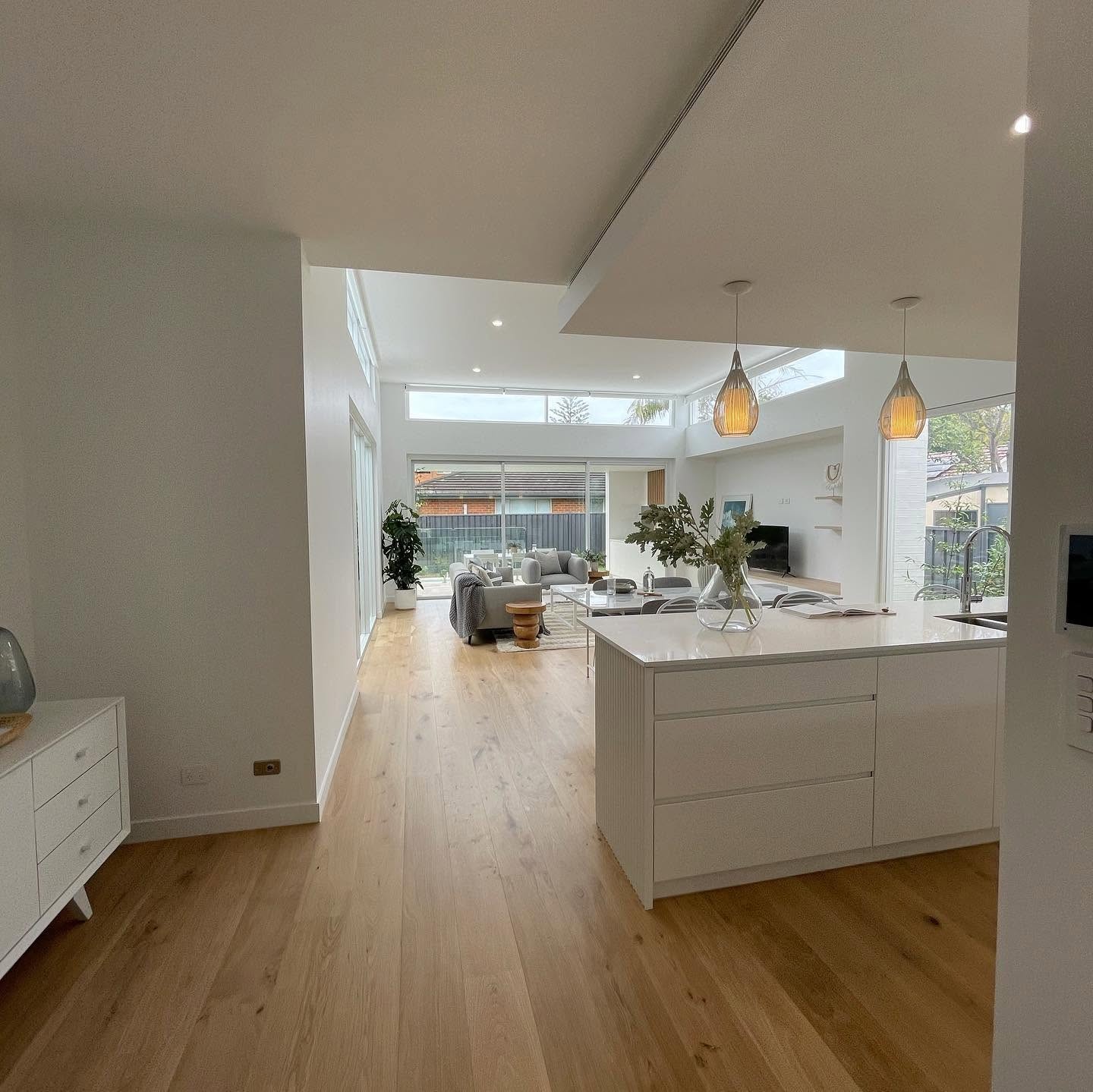 Open-plan kitchen flowing into living with light oak running throughout